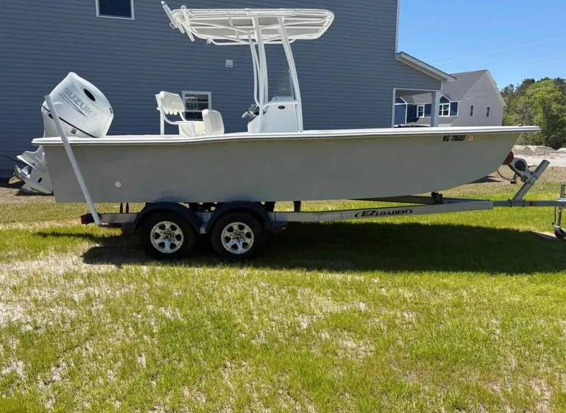 Slide: The Image of 2021 Savannah SS21 boat on trailer, parked on grass near a house. - 2