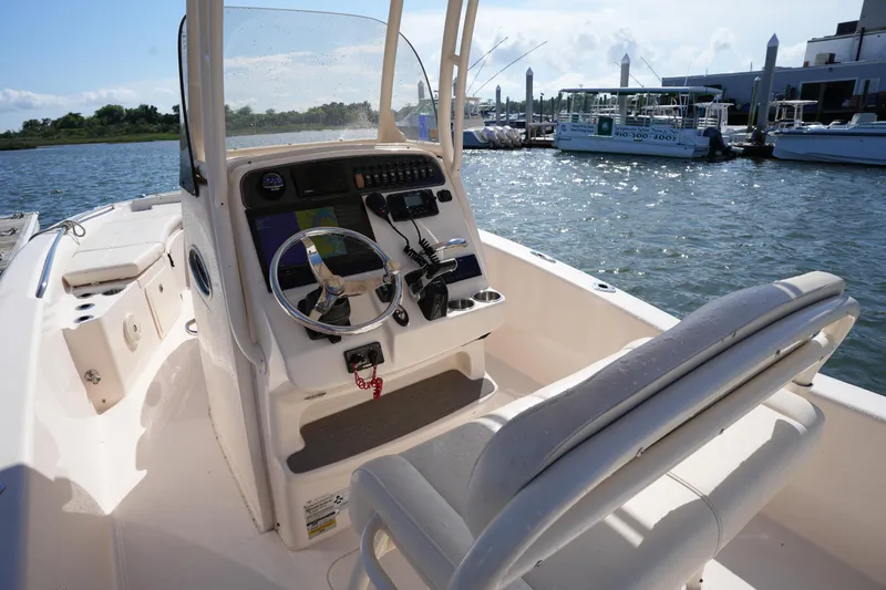 Slide: The Image of 2016 Grady-White 251 Coastal Explorer boat interior with steering console and seating, docked by the water. - 16