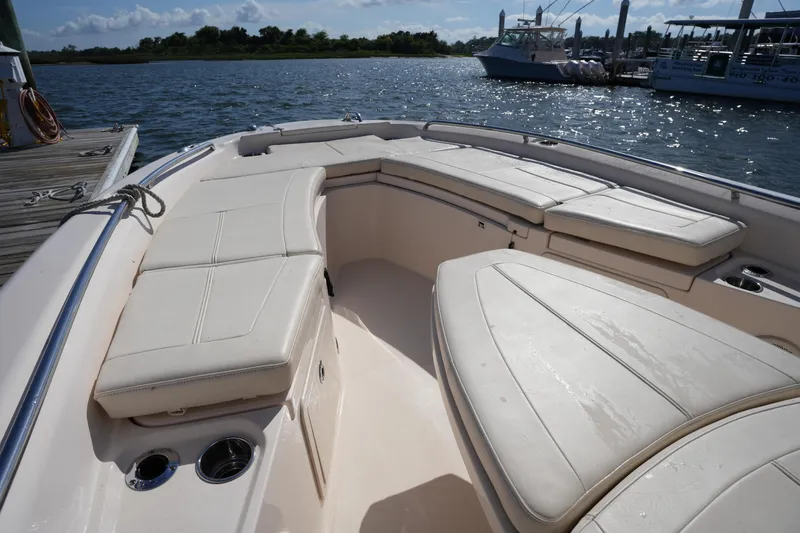 Slide: The Image of 2016 Grady-White 251 Coastal Explorer boat interior with cushioned seating, docked by the water. - 30