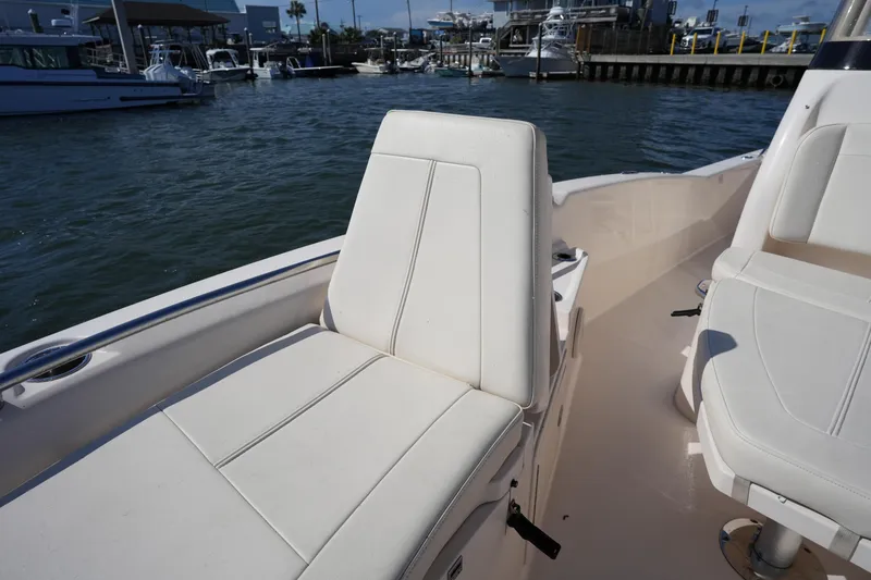 Slide: The Image of 2016 Grady-White 251 Coastal Explorer boat interior with white seating, docked at marina. - 32