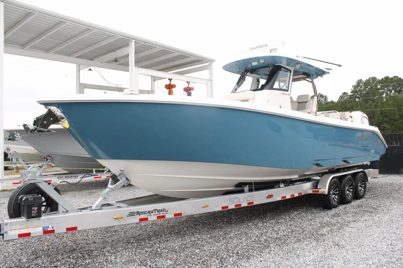 Slide: The Image of 2024 Solace 32 CS boat on trailer, blue hull, parked outdoors. - 1