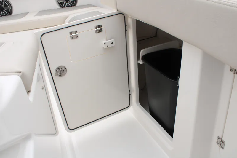 Slide: The Image of 2024 Solace 32 CS boat storage compartment with trash bin, open door, and sleek white interior. - 15