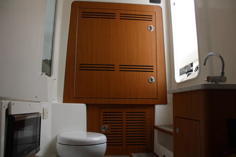Slide: The Image of 2024 Solace 32 CS boat interior with wooden cabinetry, toilet, and sink. - 18