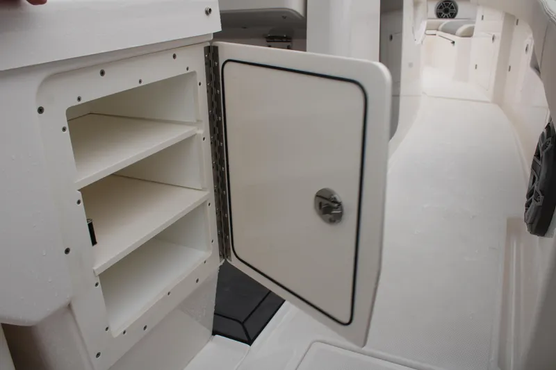 Slide: The Image of 2024 Solace 32 CS boat interior storage compartment with open door and shelves. - 37