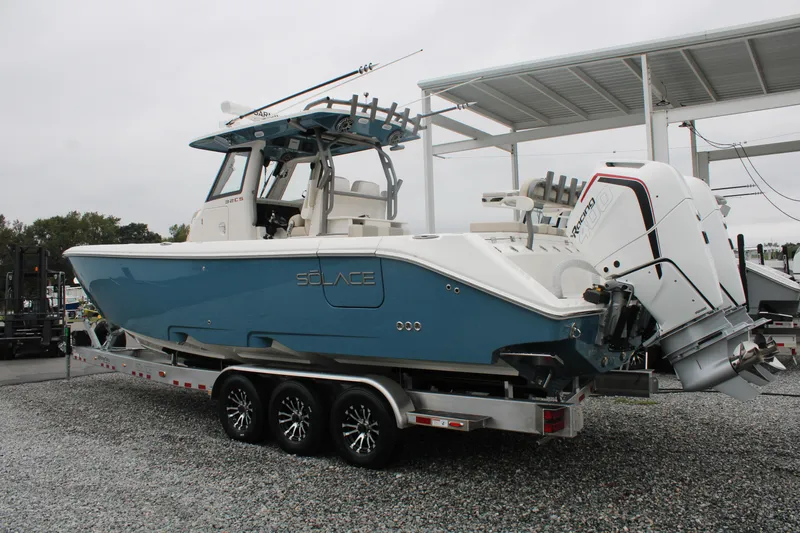 Slide: The Image of 2024 Solace 32 CS boat on trailer, featuring dual outboard engines, parked outdoors. - 4