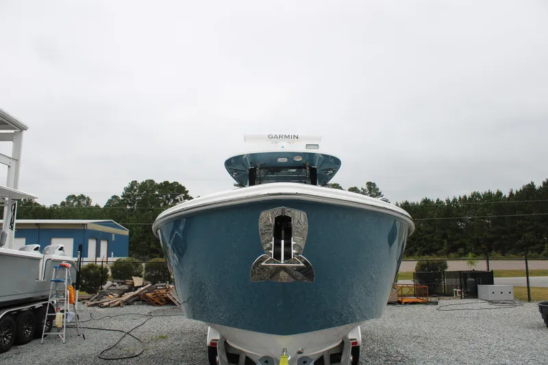 Slide: The Image of 2024 Solace 32 CS boat, front view, blue hull, parked on gravel lot. - 5
