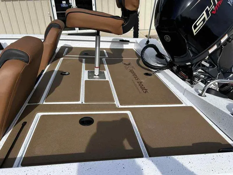 Slide: The Image of 2025 Xpress H18B boat interior with brown seating and motor. - 10