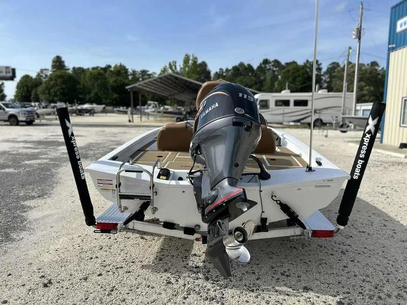Slide: The Image of 2025 Xpress H18B boat with Yamaha outboard motor, parked outdoors on gravel. - 7