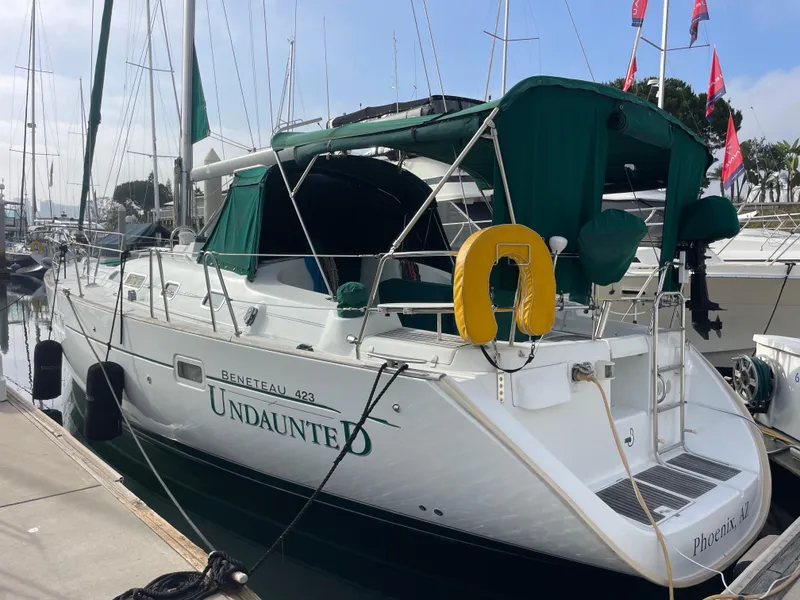 Slide: The Image of 2004 Beneteau 423 sailboat docked, featuring green canopy and yellow life preserver. - 16