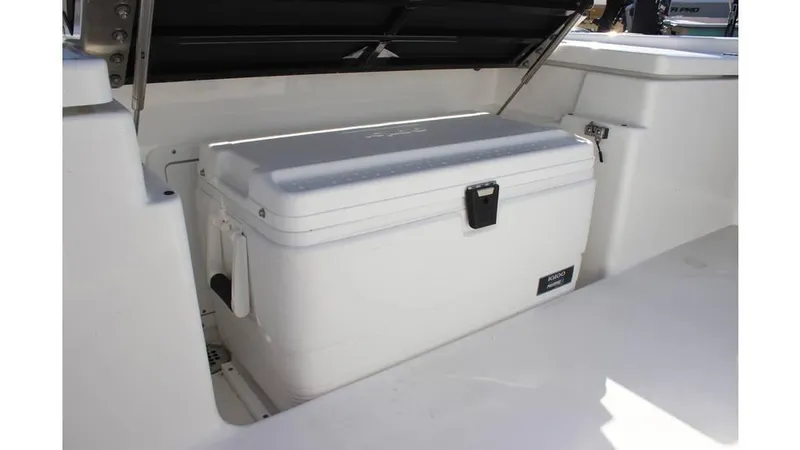 Slide: The Image of 2025 Crevalle 26 HCO boat storage compartment with a white cooler inside. - 13