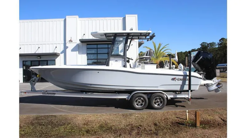 Slide: The Image of 2025 Crevalle 26 HCO boat on trailer, parked outside a building. - 2