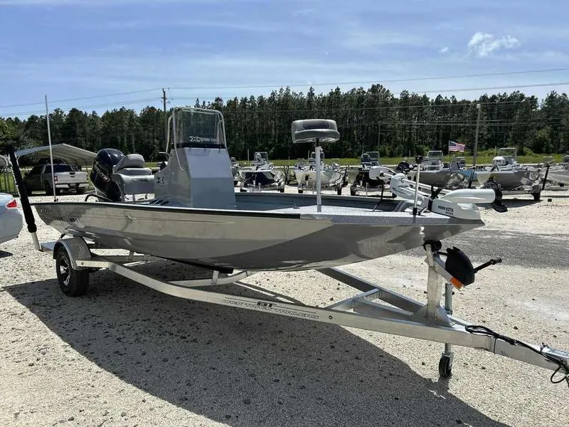Slide: The Image of 2025 Xpress H190B boat on trailer in outdoor lot, surrounded by trees and other boats. - 5