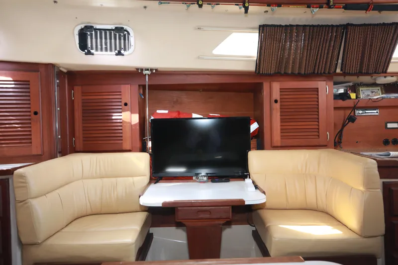 Slide: The Image of Interior of 1988 Catalina 36 sailboat with beige seating and a TV. - 22