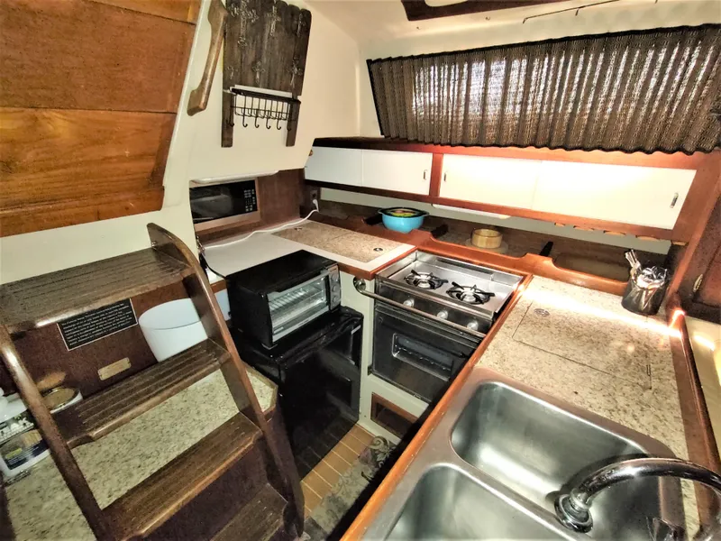 Slide: The Image of Interior of 1988 Catalina 36 sailboat kitchen with stove, sink, and wooden cabinetry. - 25