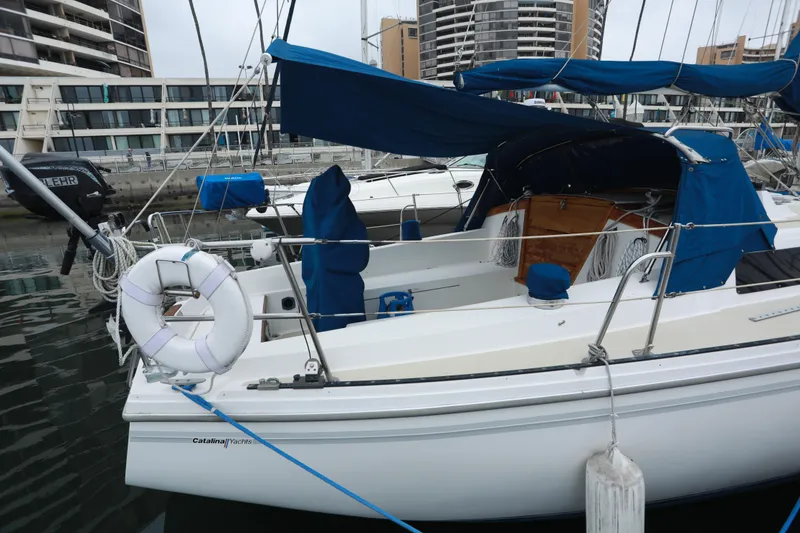 Slide: The Image of 1988 Catalina 36 sailboat docked in marina with blue canopy and life preserver. - 3