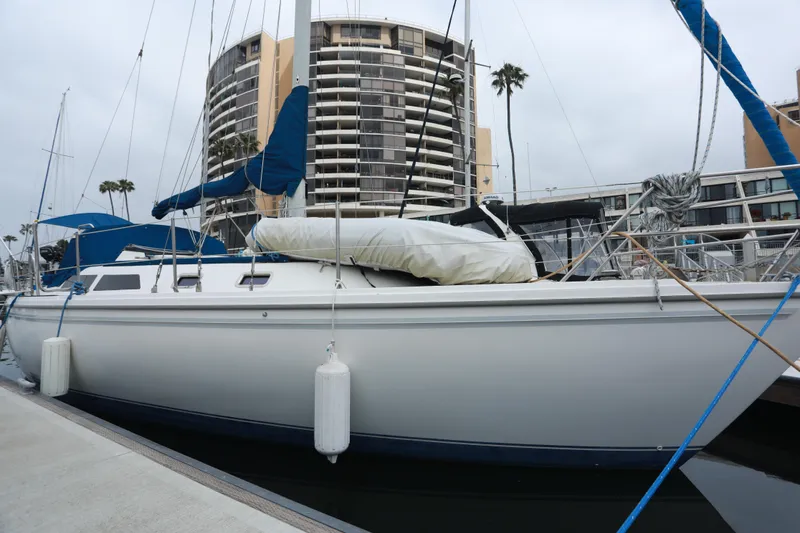 Slide: The Image of 1988 Catalina 36 sailboat docked in marina, with modern buildings in the background. - 4