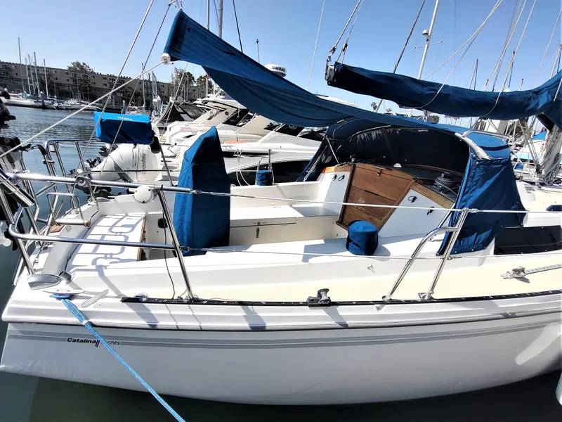 Slide: The Image of 1988 Catalina 36 sailboat docked in marina, featuring blue canvas covers and sleek white hull. - 8