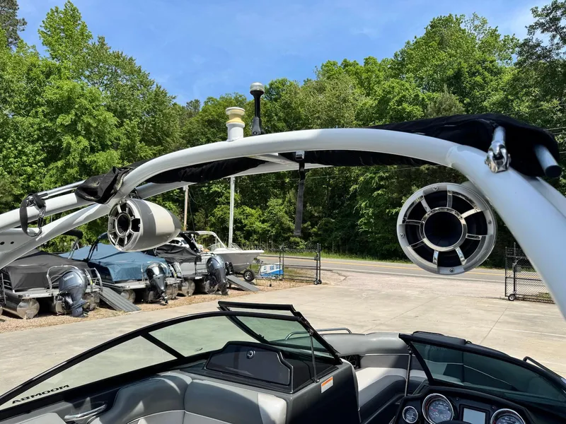 Slide: The Image of 2014 Moomba Mondo boat with speakers, parked outdoors near trees and other boats. - 12