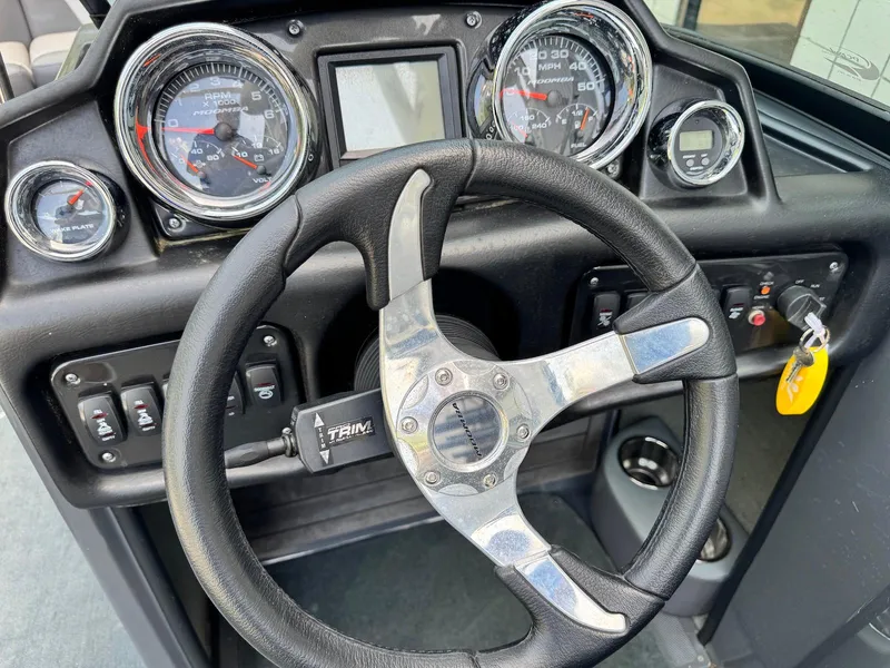 Slide: The Image of Steering wheel and dashboard of a 2014 Moomba Mondo boat, featuring gauges and controls. - 17