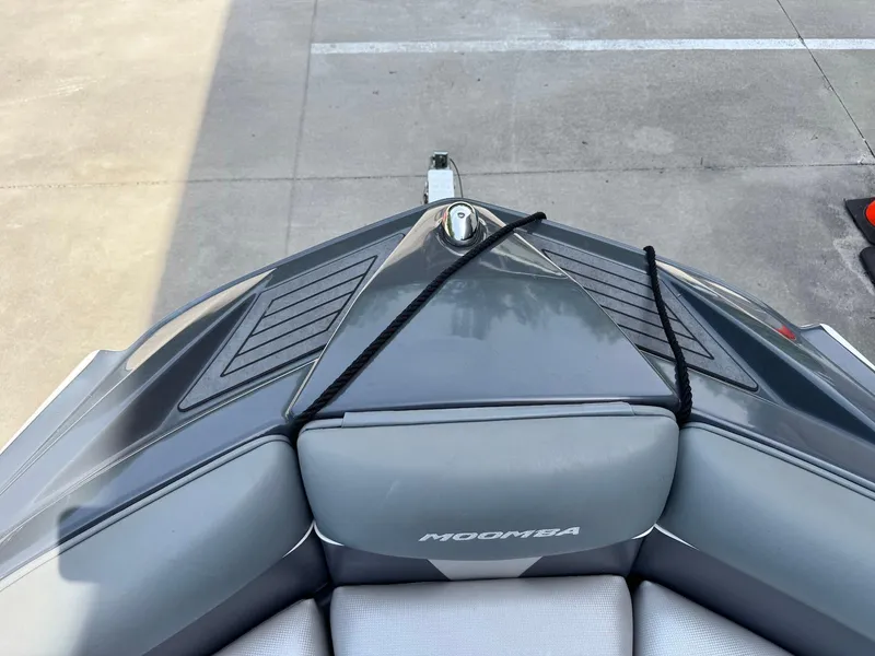Slide: The Image of 2014 Moomba Mondo boat bow with gray seating and black rope, parked on concrete. - 33