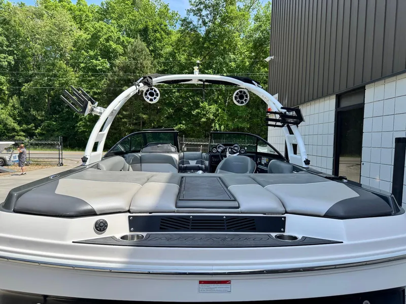 Slide: The Image of 2014 Moomba Mondo boat with sleek seating and wakeboard tower, parked outdoors. - 4