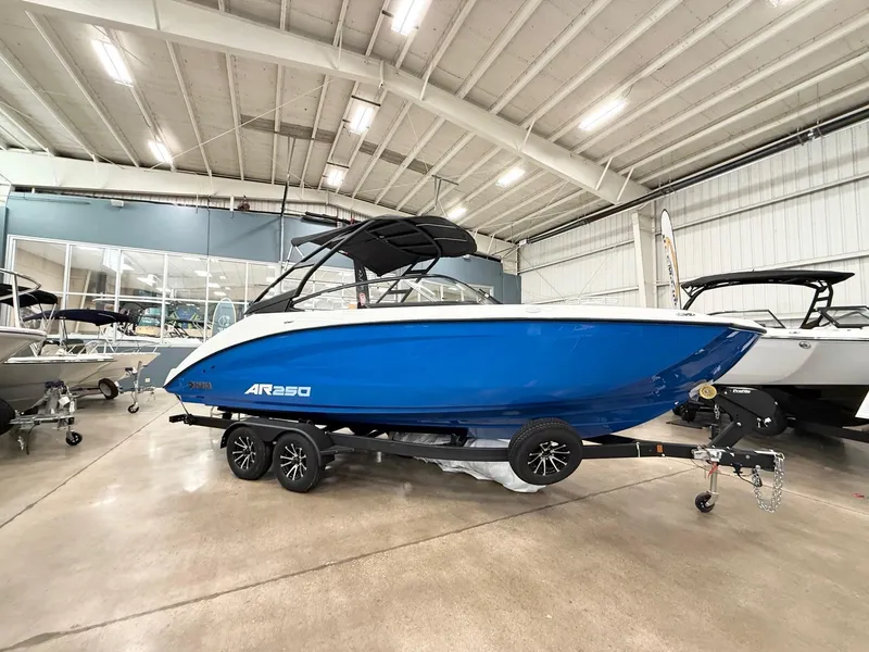 The Image of 2025 Yamaha AR250 boat in showroom, blue and white design, on trailer. - 0