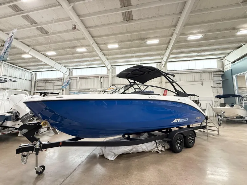 Slide: The Image of 2025 Yamaha Boats AR250 in showroom, blue hull, on trailer, indoor display. - 2