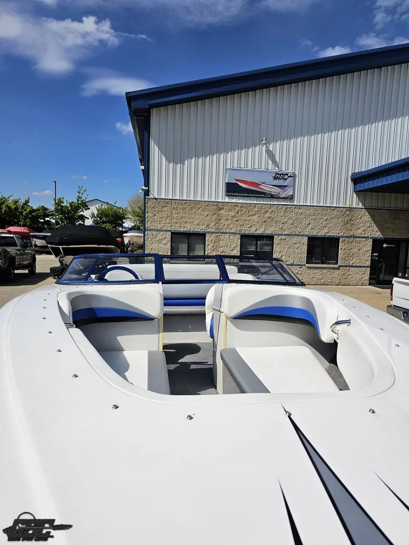 Slide: The Image of 2012 Checkmate ZT 230 BR boat with blue accents, parked outside a dealership under a clear sky. - 16