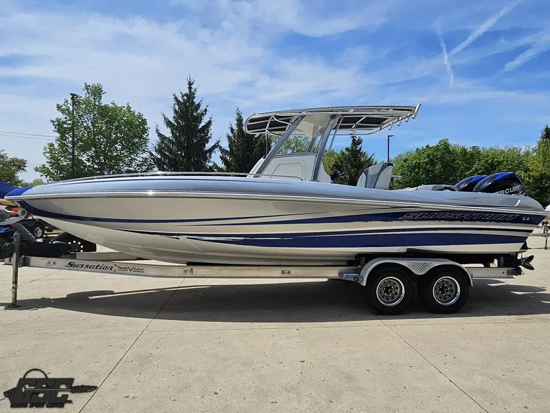 Slide: The Image of 2017 Sunsation 29 CCX boat on trailer, silver and blue design, parked outdoors. - 18