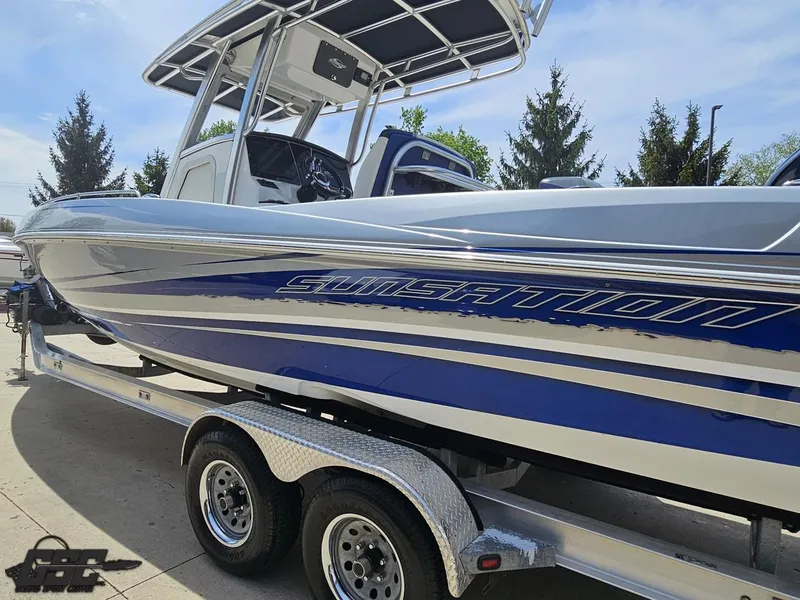 Slide: The Image of 2017 Sunsation 29 CCX boat on trailer, blue and silver design, parked outdoors. - 21