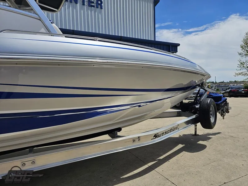 Slide: The Image of 2017 Sunsation 29 CCX boat on trailer, silver with blue accents, parked outdoors. - 4