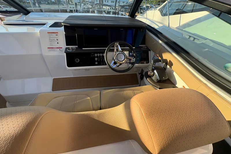 Slide: The Image of 2026 Sea Ray Sundancer 320 Outboard helm with modern controls and tan seating. - 10
