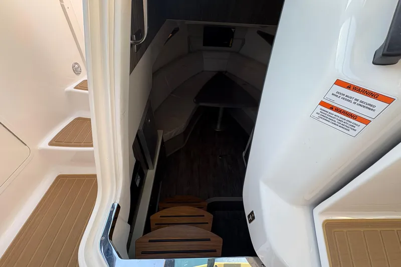 Slide: The Image of Interior view of 2026 Sea Ray Sundancer 320 Outboard cabin entrance with warning labels. - 17