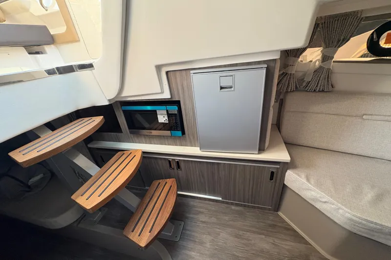 Slide: The Image of Interior of 2026 Sea Ray Sundancer 320 Outboard with stairs, microwave, and seating area. - 19