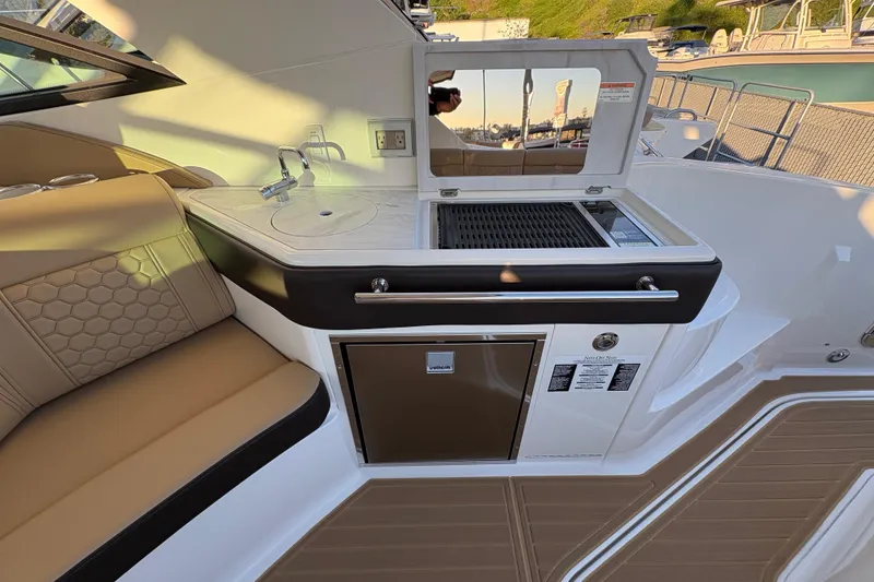 Slide: The Image of 2026 Sea Ray Sundancer 320 Outboard interior with kitchenette and seating area. - 8