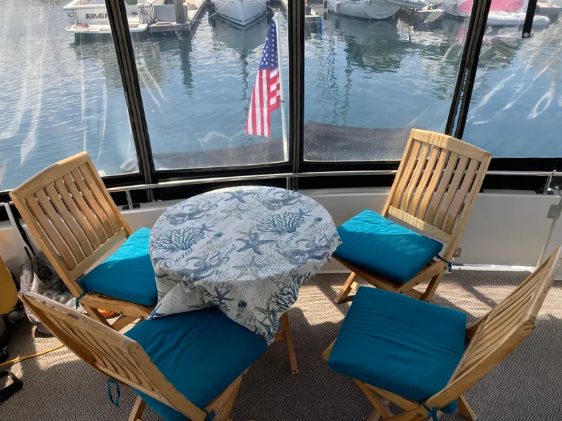 Slide: The Image of 2001 Carver 396 Aft Cabin interior with table, chairs, and marina view. - 21