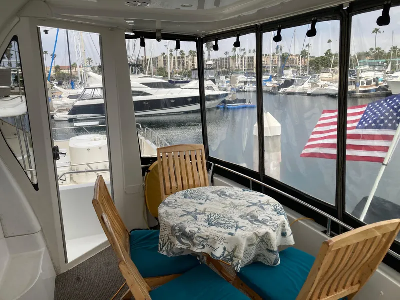 Slide: The Image of 2001 Carver 396 Aft Cabin yacht interior with table, chairs, and marina view. - 22