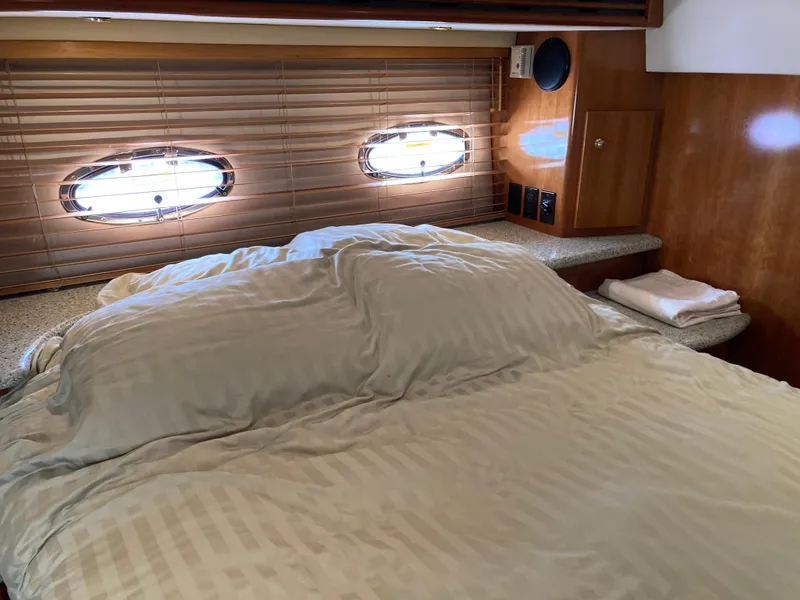 Slide: The Image of 2001 Carver 396 Aft Cabin bedroom with cozy bedding and porthole windows. - 35