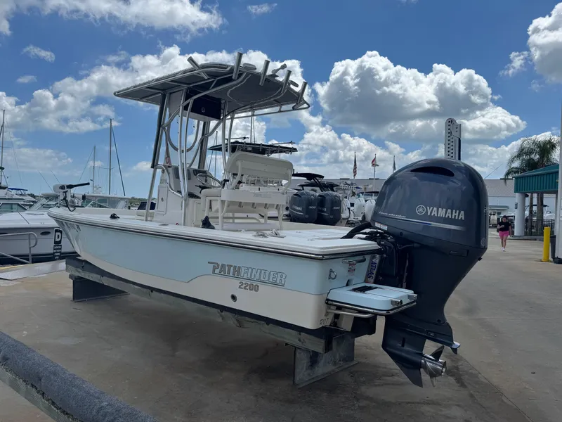 Slide: The Image of 2014 Pathfinder 2200 TRS boat with Yamaha outboard motor, docked under a cloudy sky. - 2
