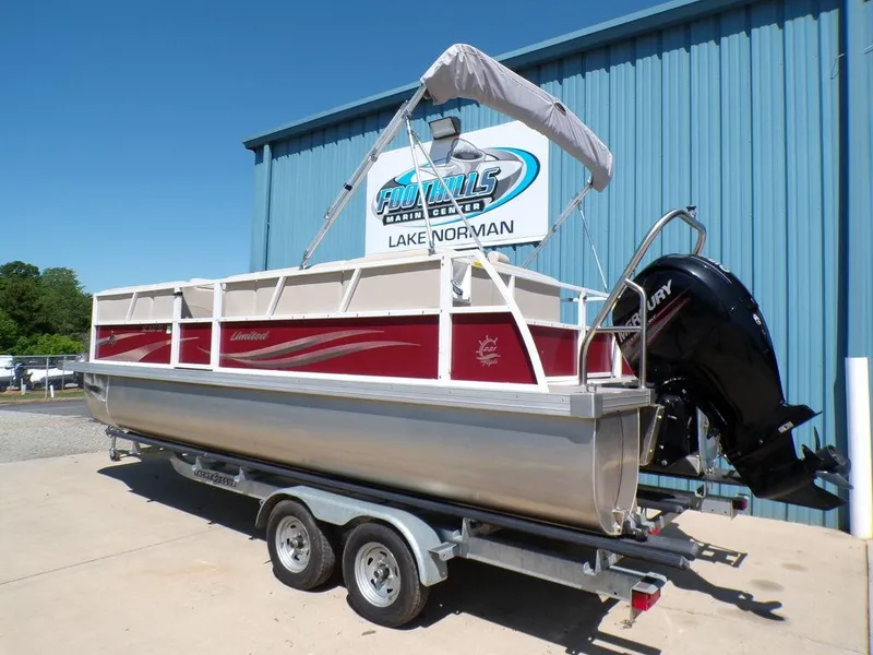 Slide: The Image of 2013 JC Limited 221 Triple pontoon boat on trailer, parked outside a blue building. - 3