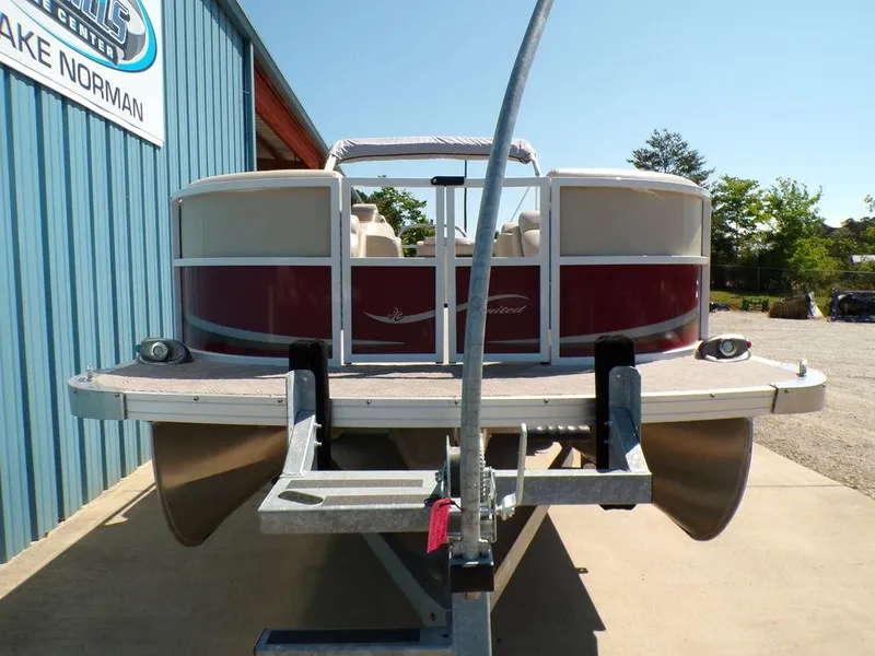 Slide: The Image of 2013 JC Limited 221 Triple pontoon boat on trailer, parked near blue building. - 4