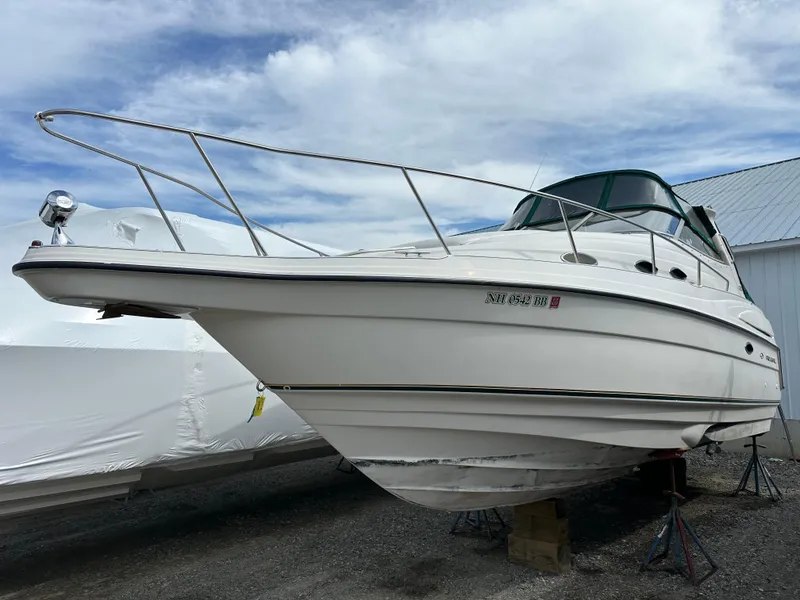 Slide: The Image of 1998 Regal 2760 Commodore boat on stands, white exterior, under cloudy sky. - 1