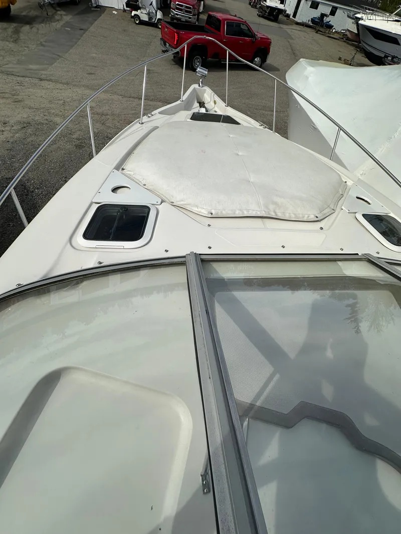 Slide: The Image of 1998 Regal 2760 Commodore boat deck with windshield and hatch, parked near vehicles. - 12