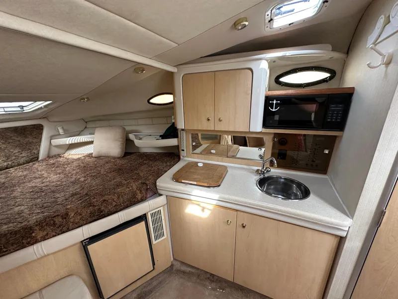 Slide: The Image of 1998 Regal 2760 Commodore cabin interior with kitchenette, bed, and storage cabinets. - 14