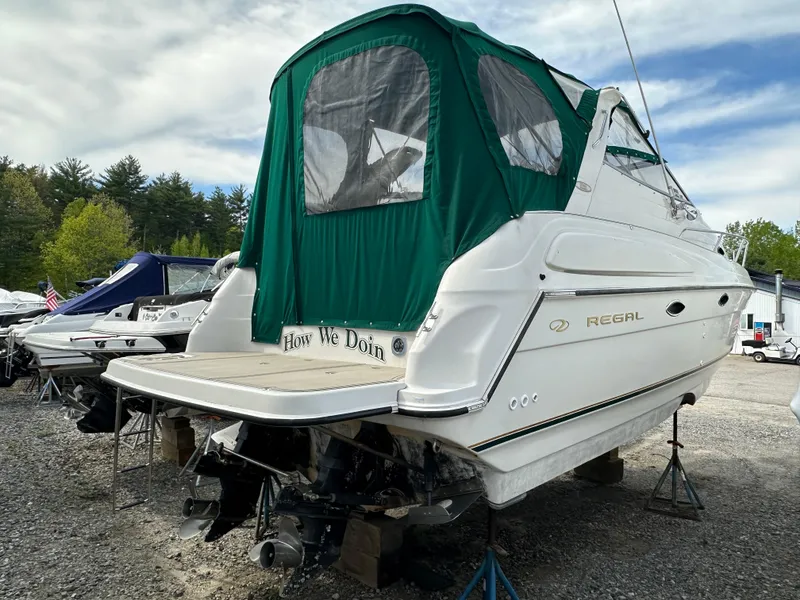Slide: The Image of 1998 Regal 2760 Commodore boat with green canopy, parked on stands. - 3