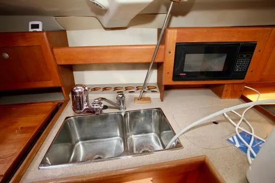 Slide: The Image of 2001 Hunter Passage 420 yacht kitchen with double sink, microwave, and wooden cabinetry. - 33