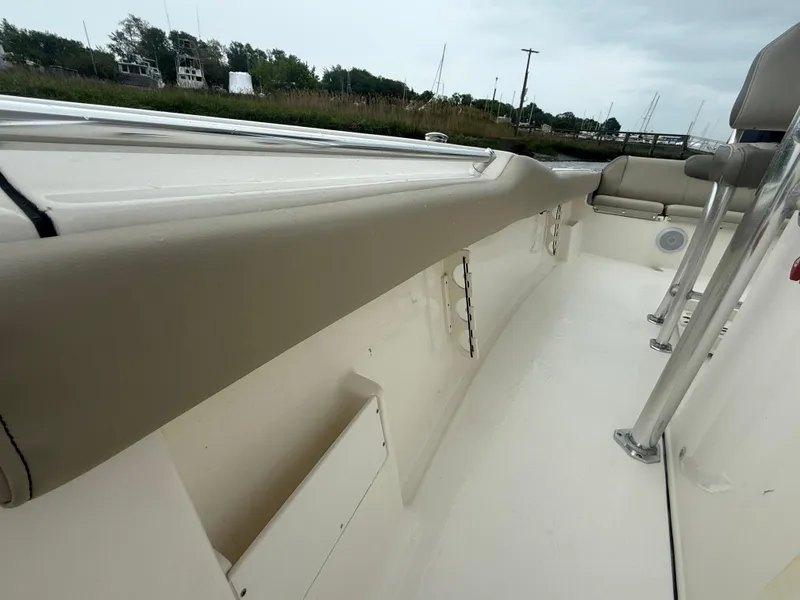 Slide: The Image of 2024 Key West 239 FS boat interior with beige seating and railing, docked near greenery. - 15