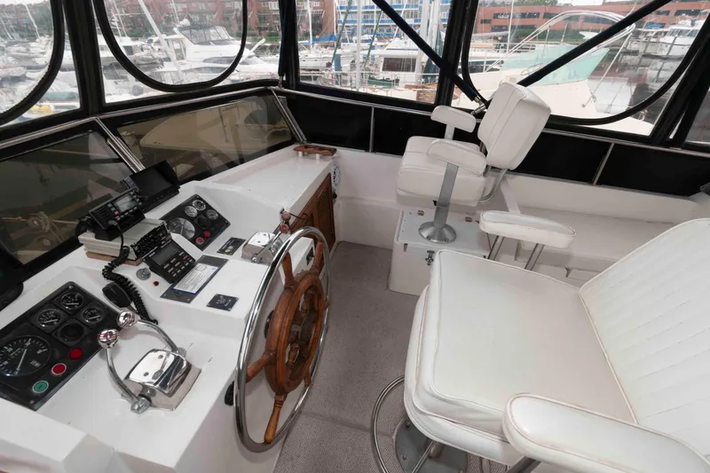 Slide: The Image of 1988 Marine Trader 48 Trawler helm with steering wheel, controls, and white seating. - 12
