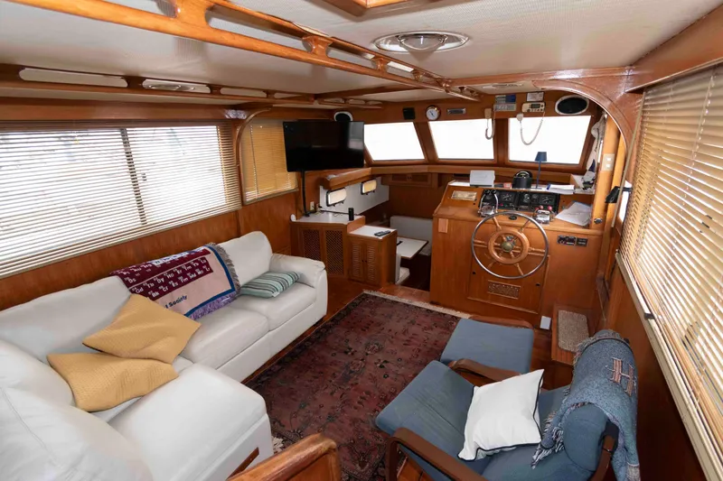 Slide: The Image of 1988 Marine Trader 48 Trawler interior with cozy seating, helm, and wooden accents. - 13