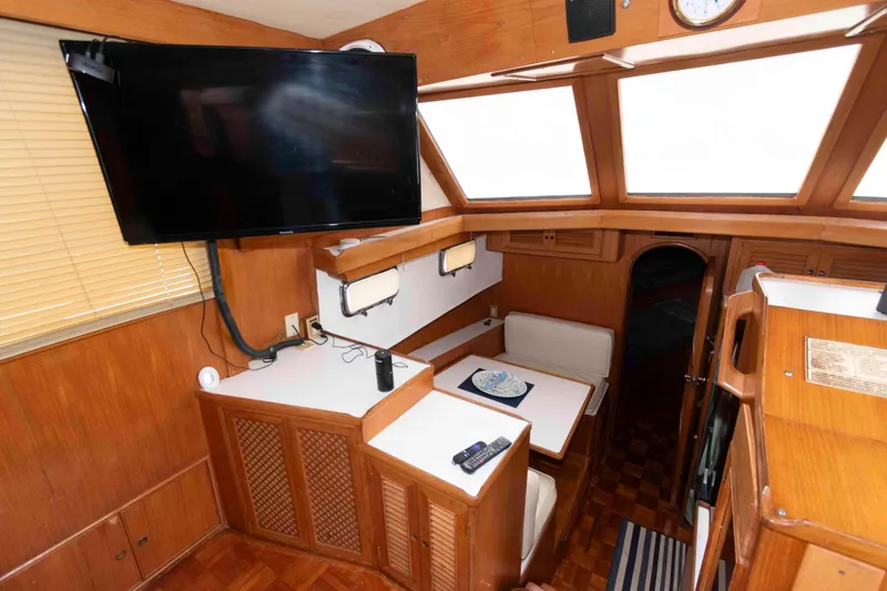 Slide: The Image of Interior of 1988 Marine Trader 48 Trawler with TV, seating, and wooden finishes. - 16